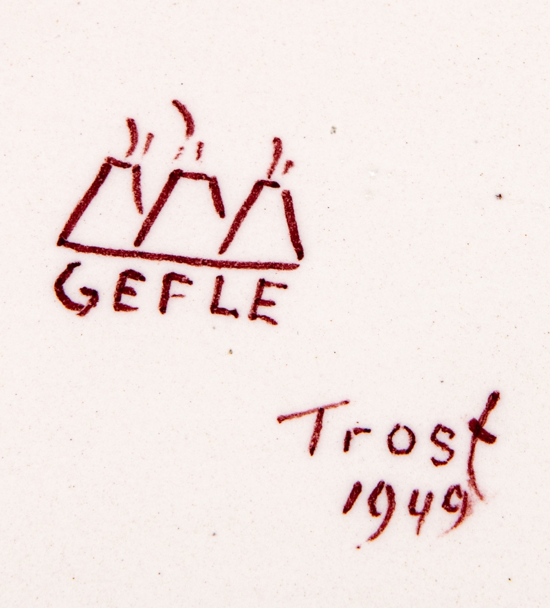 Bricka av flintgods, formgiven av Arthur Percy för Gefle Porslinsfabrik, modell -A. Uppsvängd, låg kant, vågig. Skivgrepena vågiga. Vit med mörkröd dekor, handmålad av Eugen Trost 1949.