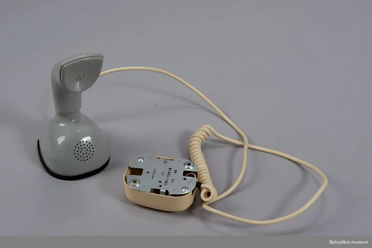 Telefonapparat Ericofon, även kallad Kobra, för AT-system, huvudapparat (med ringklocka), anknytningsapparat till växel (med ringklocka) och sidoapparat (utan ringklocka). Bordsmodell, m57, av grå termoplast utan inbyggd ringklocka och med alla komponenter sammansatta till en enhet. När telefonen används som huvud- eller anknytningsapparat ansluts en separat väggmonterad avstängningsbar ringklocka. Fingerskivan av plast är försänkt i apparatfoten. Klykfunktionen är realiserad med en knapp som skjuter ut ur fingerskivans centrum och påverkas av apparatens tyngd.