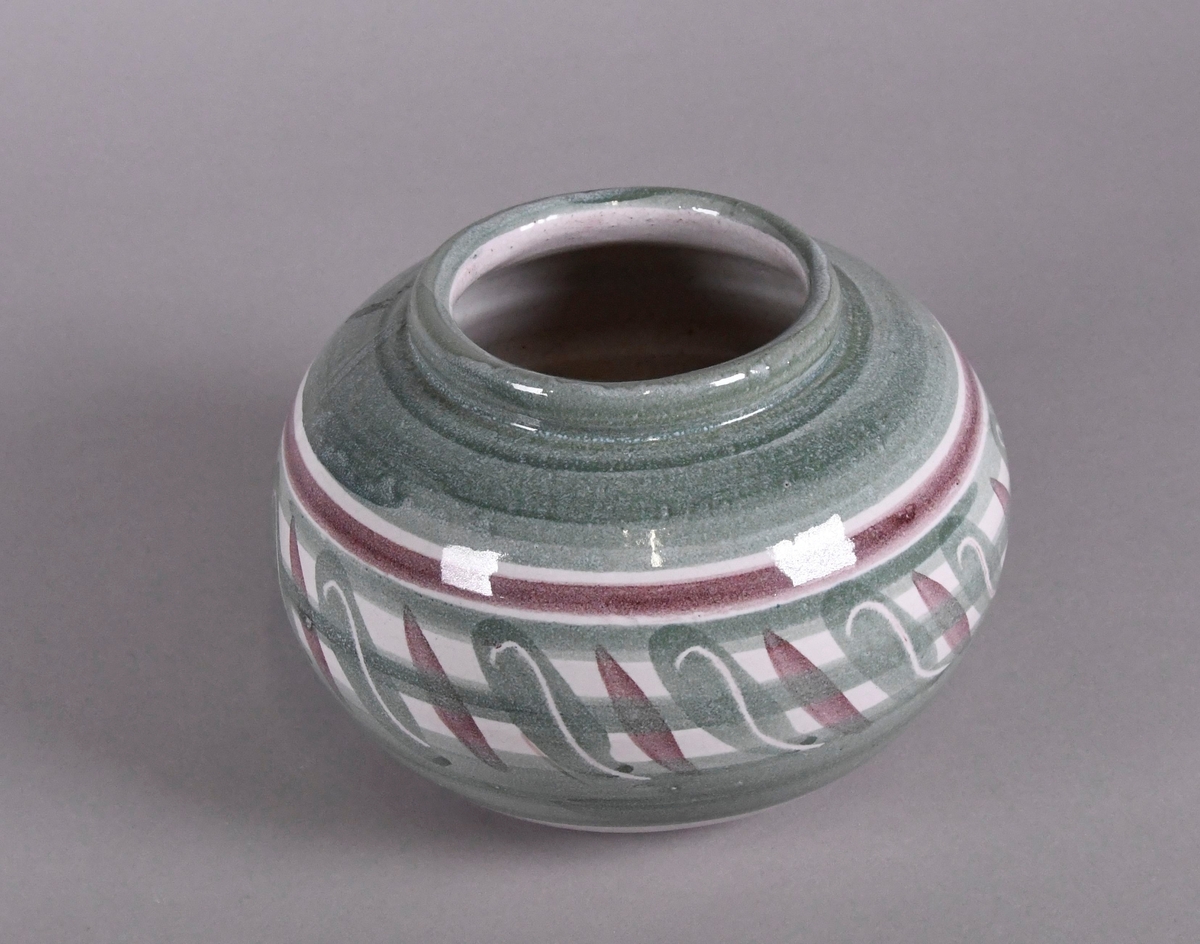 Vase av glassert keramikk. Vasen har rund form, med en noe opphevet krage. Vasen har grønn og lilla håndmaling. På midten går det en borde med skråliggende olivendråper, hvorpå den grønne har en hvit s-lignende strek inni.