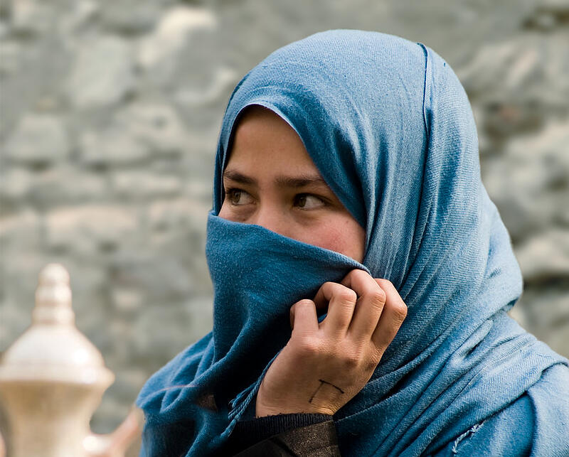 Nærbilde av ei afghansk jente, delvis tildekket av et blått sjal.