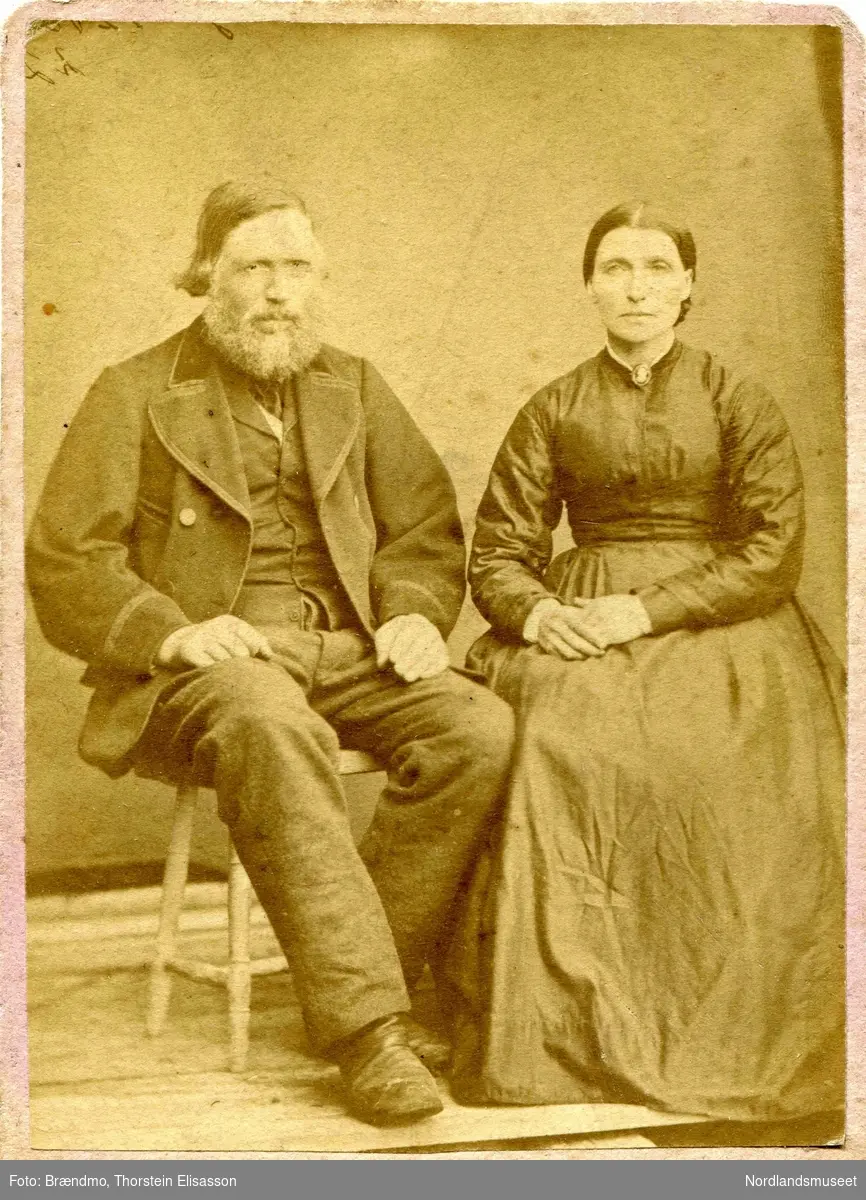 Portrett av et ukjent ektepar, mannen med skjegg og langt hår sitter på en krakk, kvinnen i sort kjole.