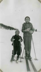 To barn på ski. De har på seg strikket lue og votter. Tekst 