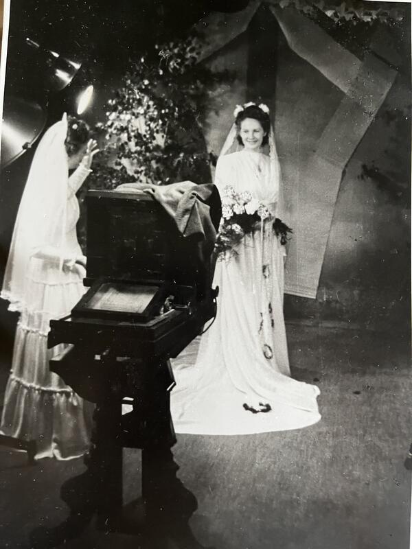Bryllupsfoto To kvinner i brudekjole i studio. I forgrunnen et storformat platekamera av eldre modell.