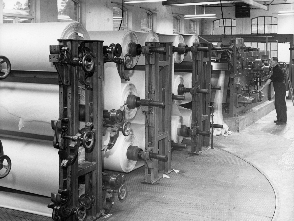 Interiør fra Drammenselvens Papirfabrikker på Geithus i Modum kommune i Buskerud.  Fotografiet viser skjæremaskinen, som her betjenes av Kristian Borgen (1900-2003). 