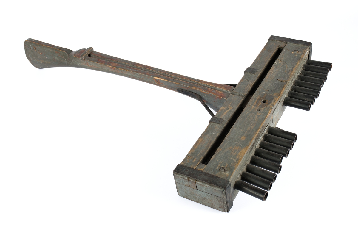 Skottbalk (orgelbössa).  Material: Trä med beslag av järn. Vapnet har 16 stycken pipor av järn. Från 1670-talet.
