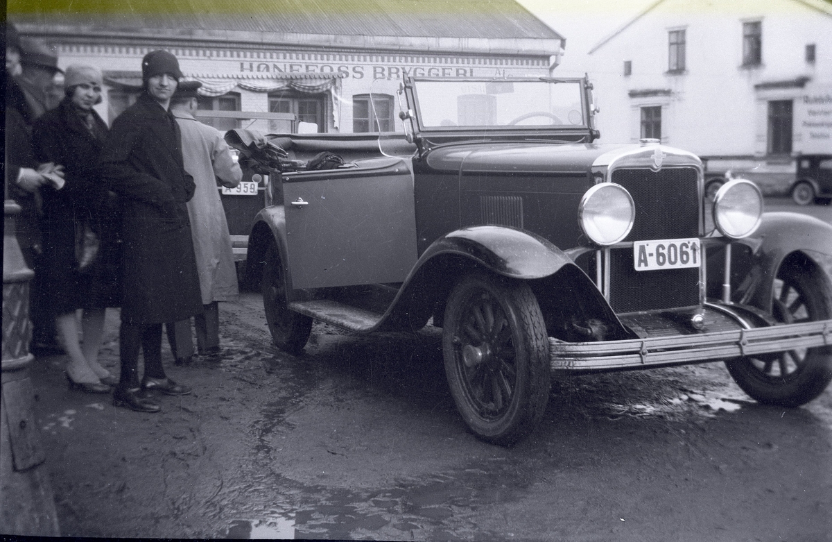 Åpen bil A-6061 og A-959 utenfor Hønefoss bryggeri, trolig tidlig på 1930-tallet.
Iflg Norges Bilbok er A-6061 en 1929-modell Chevrolet med eier Hallgrim Galberg, A-959 er oppført i Norges Bilbok 1935 som Buick 1930 modell med eier Mathilde Lien.