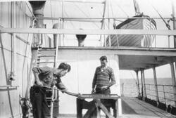 To menn spiller kurong (?) på dekket til et skip.
