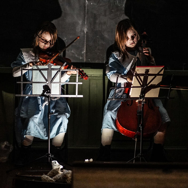 To jenter i halloweenkostyme spiller fiolin.