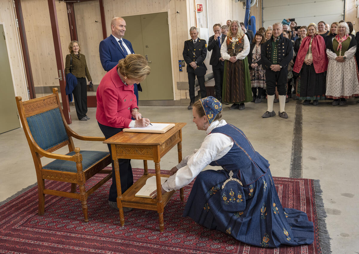 Hennes Majestet Dronning Sonja blir mottatt av magasinforvalter Toril Skaraas Hofseth, og signerer besøksprotokollen ved inngangen til konserveringsverkstedene.