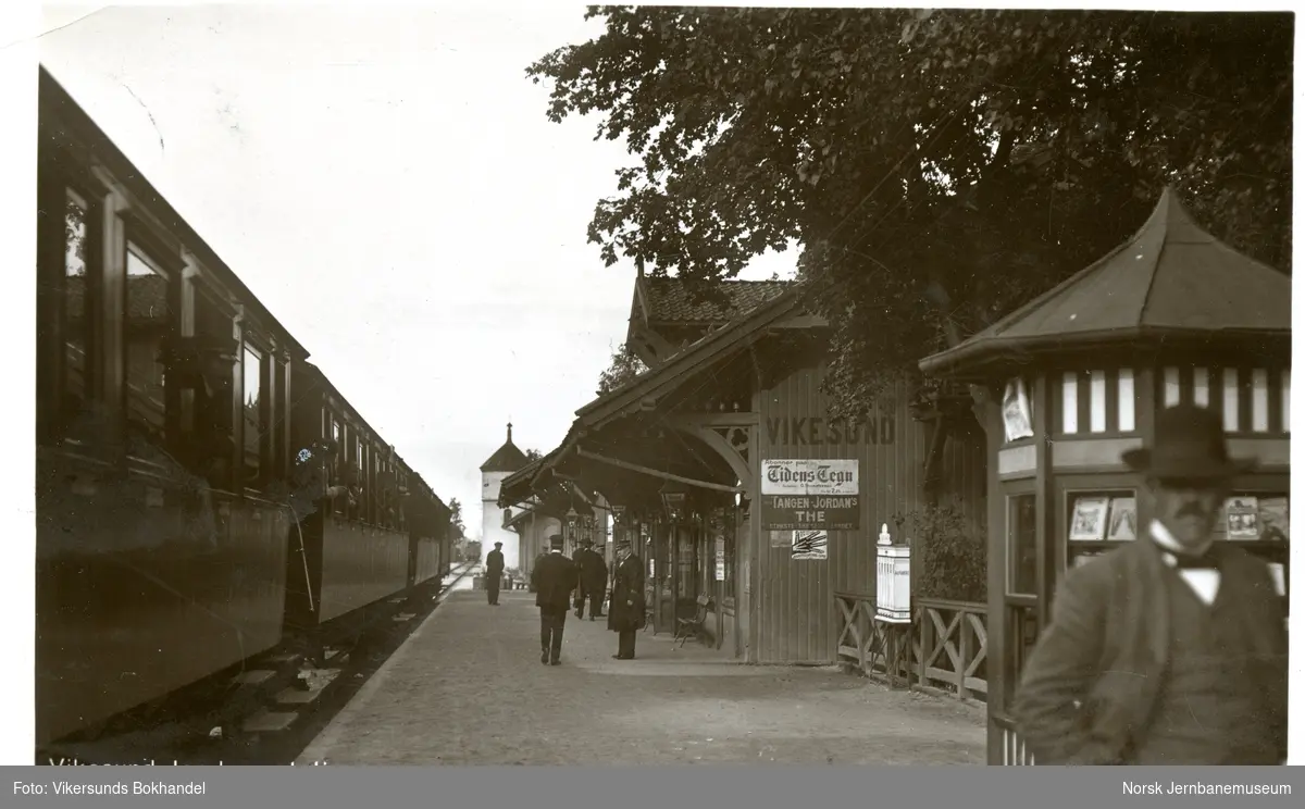 Vikersund (Vikesund) stasjon. Stasjonsbetjening og reisende på plattformen. Persontog i spor 1