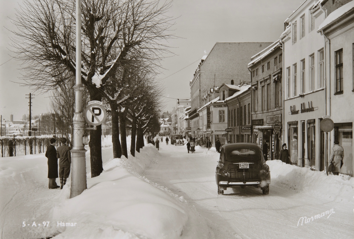 Postkort, Hamar, Strandgata 13, Støkkens Bokhandel, E. Hammerstad, C. R. Larsen & Co, vinter med brøytekanter, en Ford drosjebil 1948 modell  med registreringsnummer D-4714,