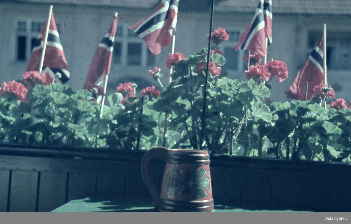 Balkong pyntet med blomster og flagg under feiringen av frigjøringsdagene 1945.