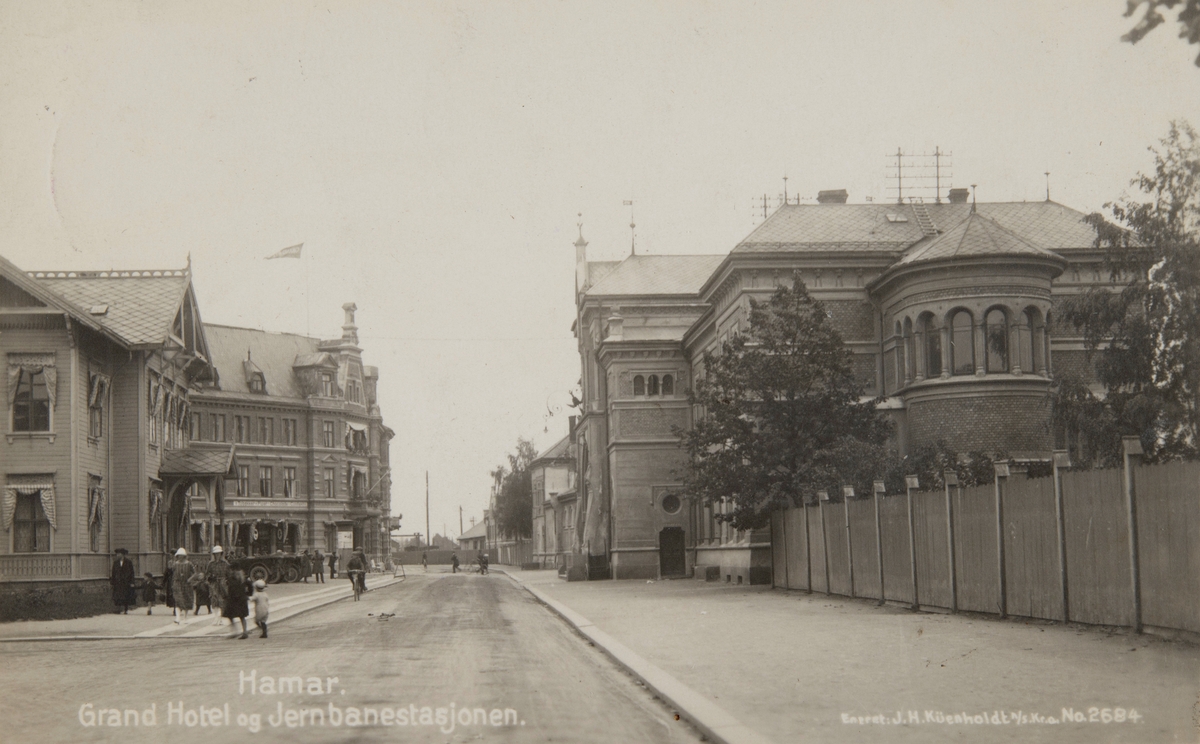 Postkort, Hamar Jernbaneplassen, Strandgata, Hamar jernbanestasjon, stasjonsbygning nr 1 til venstre og stasjonsbygning 3 til høyre, i midten Grand Hotell,
