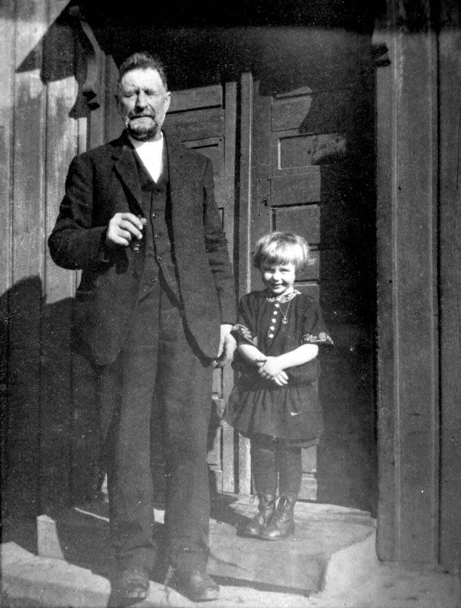 Portrett av Thorvald Andersen Hem, far til Olav Hem, og en liten pike som heter Ellen Hem, på trappehella til framhuset på Hem