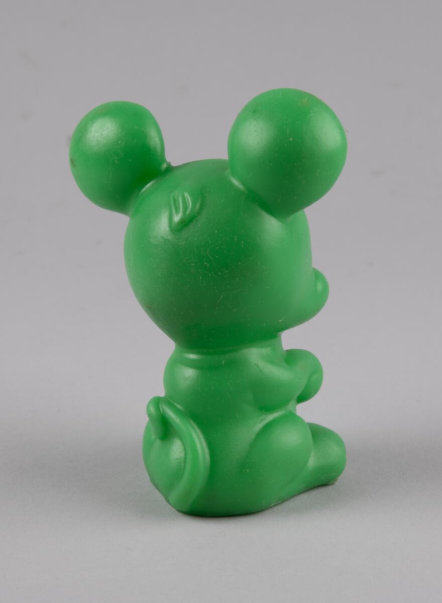 Leketøy av mykplast i form av en sittende, grønn mus med hvite og svarte markeringer.