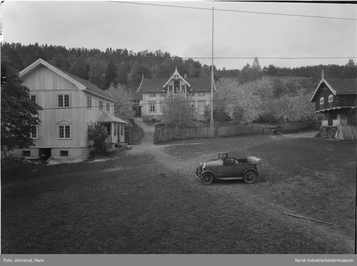 Gårdsplass på gården Seljord i Heddal med to bolighus og ett stabbur. Bil stående foran ett av bolighusene. Flaggstang midt på tunet. Ett av bolighusene er dekorert med snekkerglede.