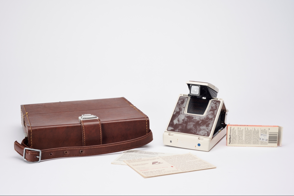 SX-70 Land Camera Model 2 ble produsert av Polaroid på 1970-tallet. Kameraet ligger i original koffert sammen med registreringskort og en pakke blits av typen Flashbar II Prismatic fra Osram.
SX-70 Land Camera revolusjonerte direktebildefotograferingen. De to første modellene er avanserte speilreflekskameraer, som kan foldes sammen. Designet var spesielt og filmen var den første med en ny type bildeframstilling. Det var det første systemet som produserte et ett-trinns direktefotografi. 
Filmene lå enkeltvis i en kassett. Hvert bilde var en forseglet pakke som inneholdt et negativ, kjemikalier og et positiv. Bildet kom automatisk ut av kameraet og kunne sees i løpet av 2 minutter, men trengte noen minutter til før det fikk sitt endelige uttrykk. I filmkassetten var også batteriet som ga strøm til kameraet og blitsen.