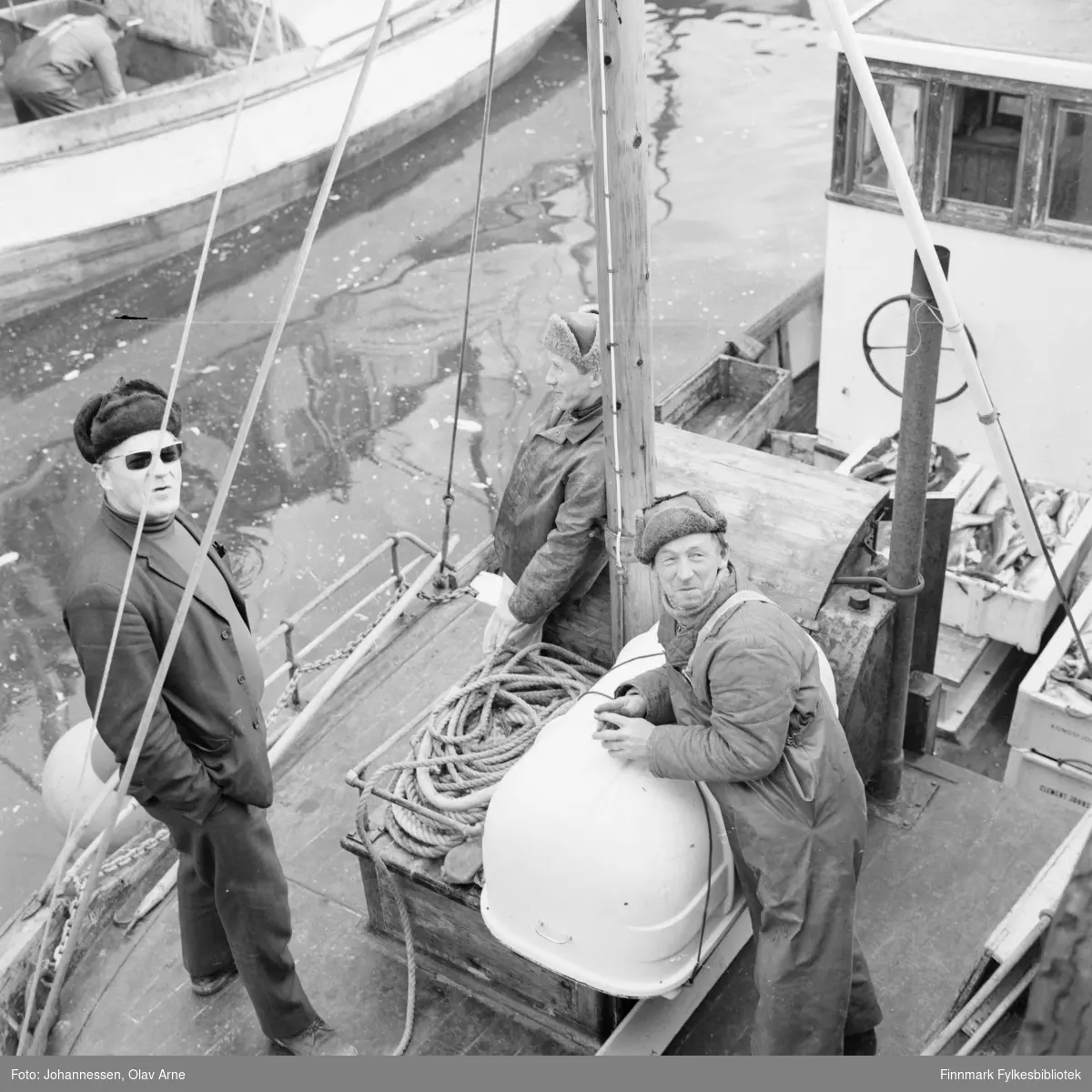 Båten Mk Junior (finnes ennå og er vernet) 

Mannen som lener seg til masten her Karl "Gutta" Pedersen (1927 - 2002) og til høyre for han er broren Rolf Pedersen (født 1919 - død 1987). De var begge fiskere og pleide å ro i lag  

Mannen helt til venstre kan være Harry Hurtig eller broren Roger Hurtig, usikker identifisering. 