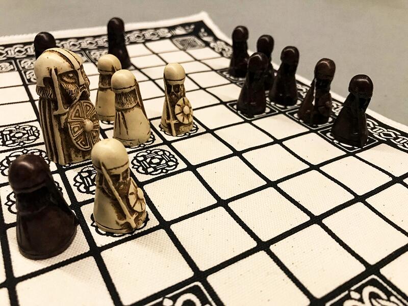 Hvite og svarte utskårne sjakkbrikker fra middelalderen på et hvitt sjakkbrett med svarte ruter