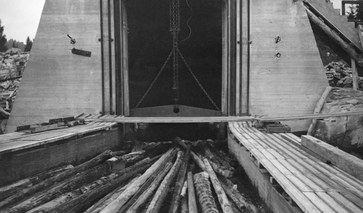 Inntaket til renna som skulle føre tømmeret forbi dammen ved Mørkfoss-Solbergfoss kraftverk i Nedre Glomma. Bildet viser tømmer på veg inn i renna. Mørkfoss-Solbergfoss kraftverk ble bygd for Oslo Lysverker og staten i perioden 1917-1924. Dammen ble plassert i en trang del av elveløpet, ved Solbergfossen, cirka 5 kilometer nedenfor det opprinnelige naturlige utløpet av Øyeren. Dermed ble den nevnte innsjøen en del av vannmagasinet til kraftverket. Anlegget fikk en fallhøyde på 22-23 meter, men dammen var på det høyeste 45 meter høy. Mens kraftstasjonen ble plassert under et stort kanalbasseng ved den østre elvebredde. Fløtinga skulle utelukkende skje gjennom ei 700 meter lang fløtingsrenne på vestsida av elva. Om lag 400 meter av denne strekningen gikk i tunnel. Renna ble bygd av impregnert trevirke. Den skulle ha en kapasitet på 12 000 stokker i timen med et vannforbruk på maksimum 15 kubikkmeter. Inntaket til renna var utstyrt med en hengslet skuff som var bygd etter noe som kalles Gran-Meyers system.