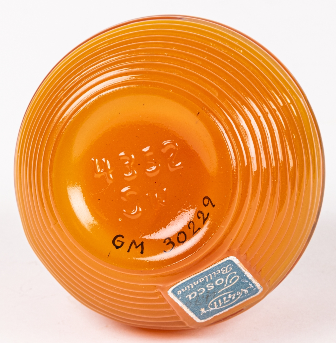 Glasburk med hårpomada (orginalförpackning). Genomskinligt glas med orangefärgad pomada. Svart lock med texten "TOSLA". På sidan en pappersetikett "4711 Tosca Brilliantine.