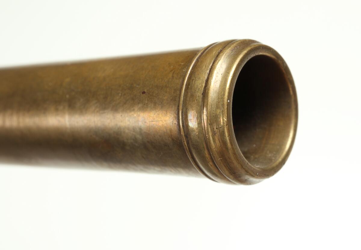 Enpipig flintlåspistol av mässing med kolv av trä, och varbygel och lås av stål. Tumplåten av stål är märkt med "P". Även kolvkappan är av stål. Boxlåset är märkt med "BUNNEY" på vänstersidan, och "LONDON" på högersidan. Pipan har Birminghams kontrollstämplar undertill. Främre delen av pipan kan skruvas loss från lådan, och pipan är slätborrad. Kolven har inläggningar, troligen i silver.
Inskrivet i huvudkatalogen 1974.