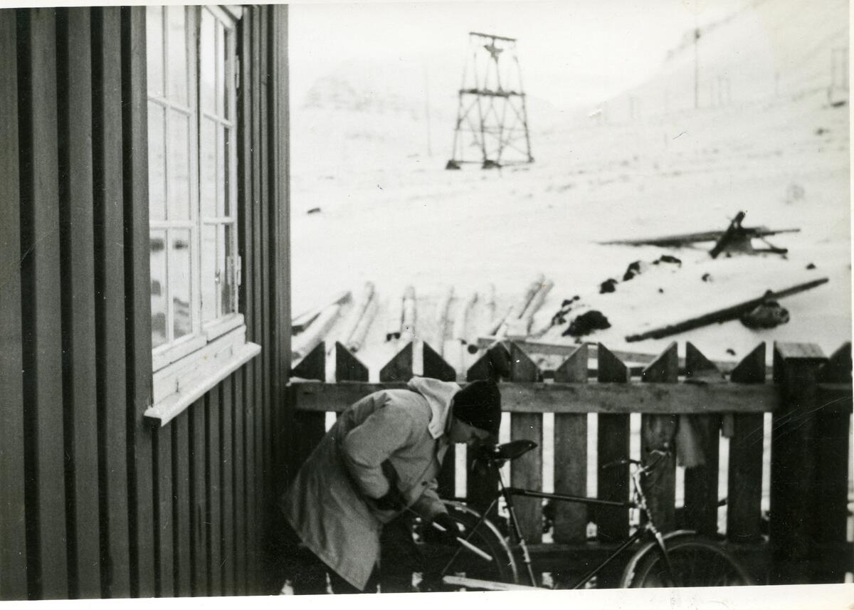 Fru Lorraine Midbøe pumper opp dekket på sykkelen  utenfor Sysselmannsgården vinteren 1963.