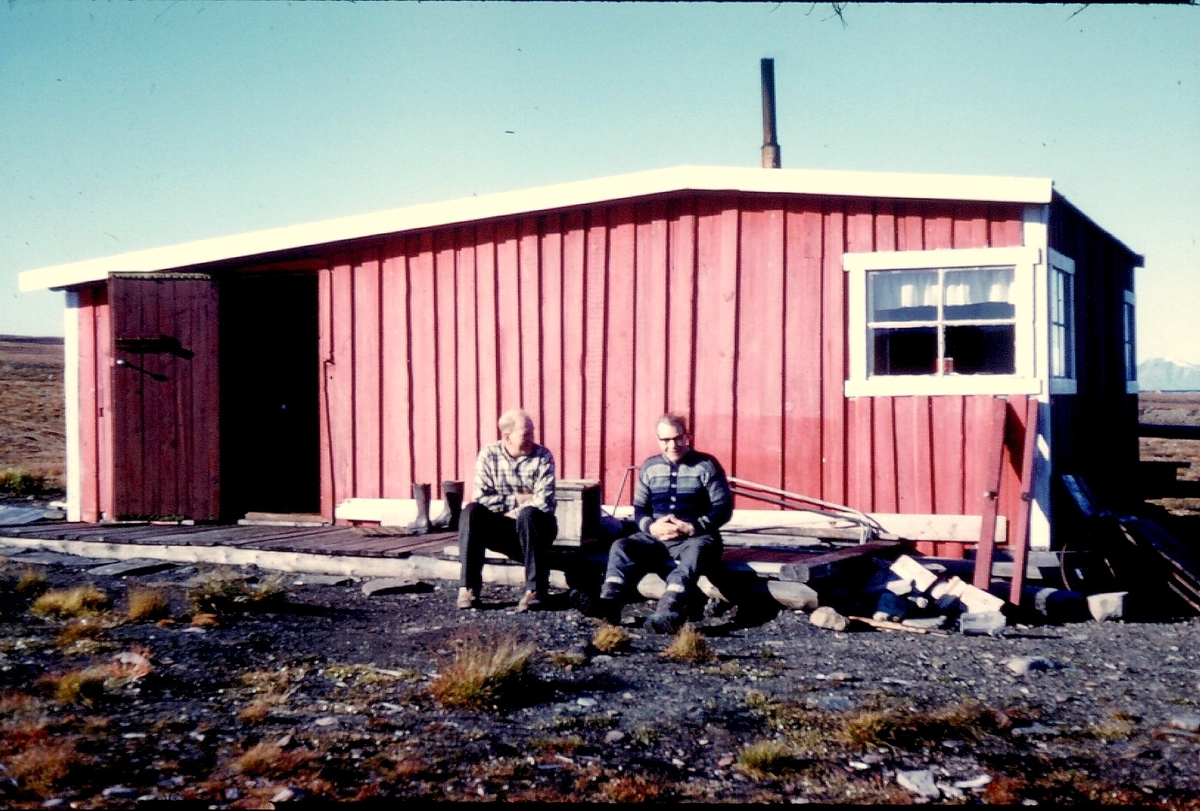 To personer sitter utenfor hytte. Bilde fra Bjørnar Nilsen, sønn av stiger Johannes Nilsen Støpseth som kom opp i 1948 og var her i 40 år.