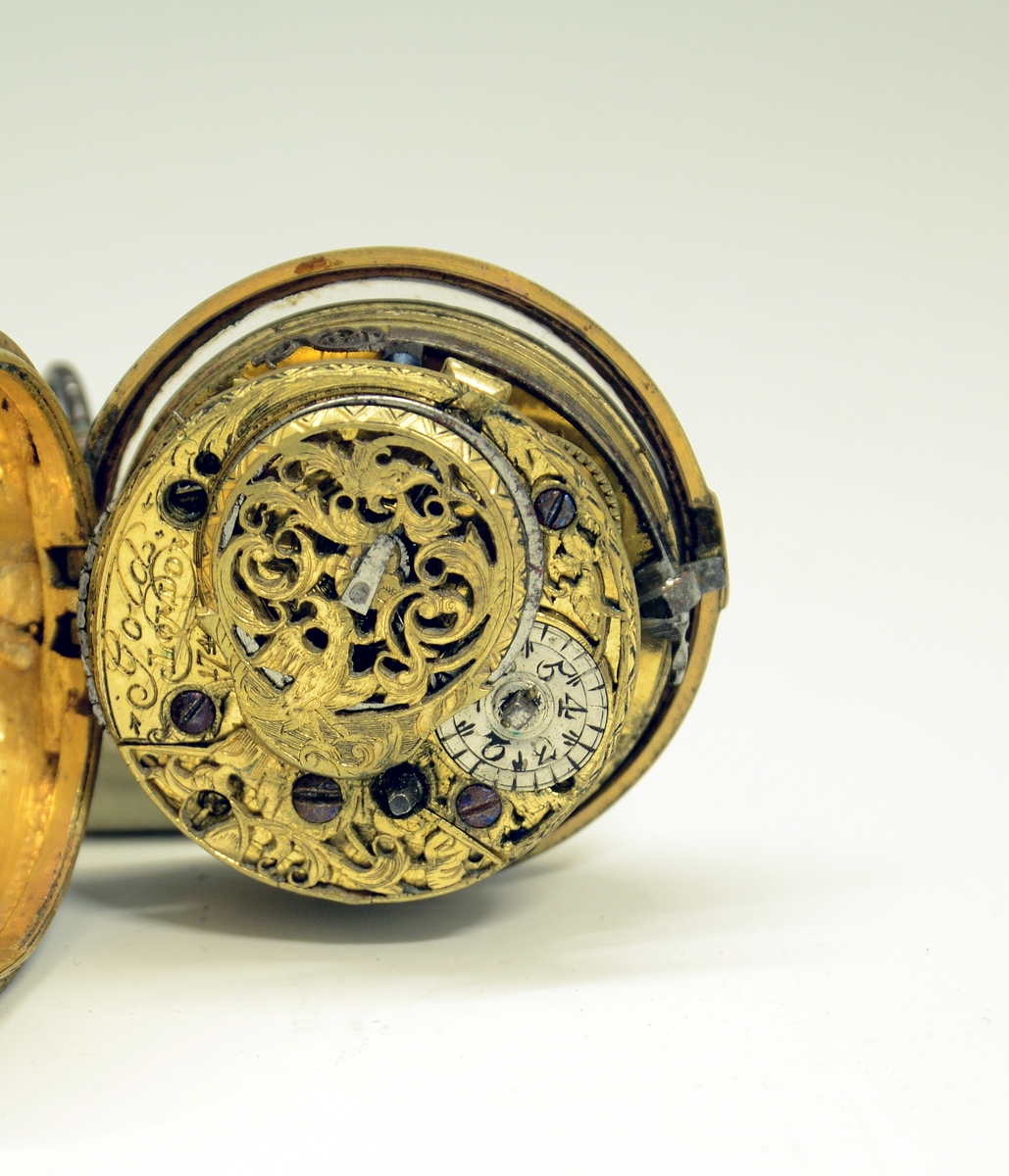 Fra protokollen: Lommeur i kasse av messing, indre kasse forgyldt, umerket plate og dæksel gjennembrutt og gravert. Merket: Gold, London 1744.
