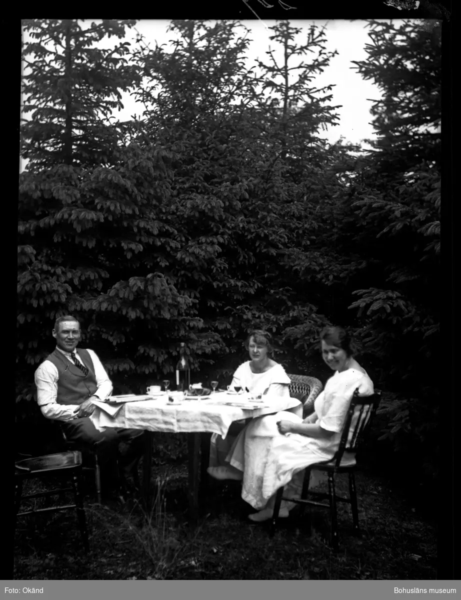 Tre personer i en trädgårdsgrupp framför ett uppdukat bord.
