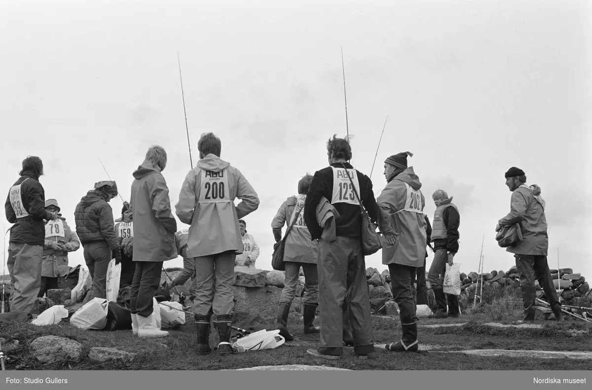 SM i Kustfiske 1975. Deltagare med nummerlappar på ryggarna.