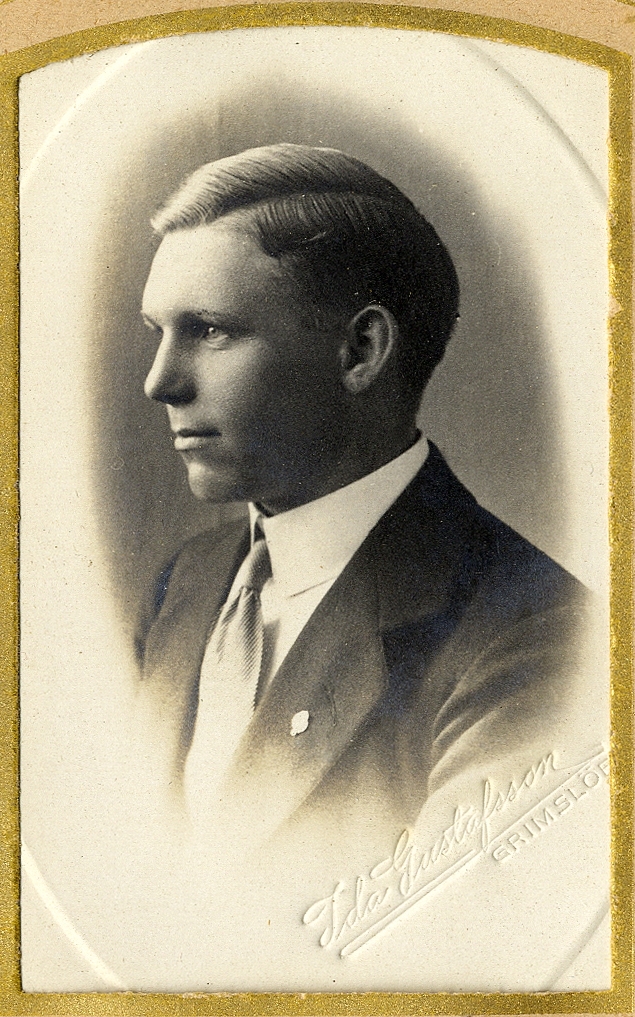 En ung man i kostym med slips.
Under fotot text med blyerts: "Johan Andersson, Lidnäs", 
Bröstbild, halvprofil/profil. Ateljéfoto.