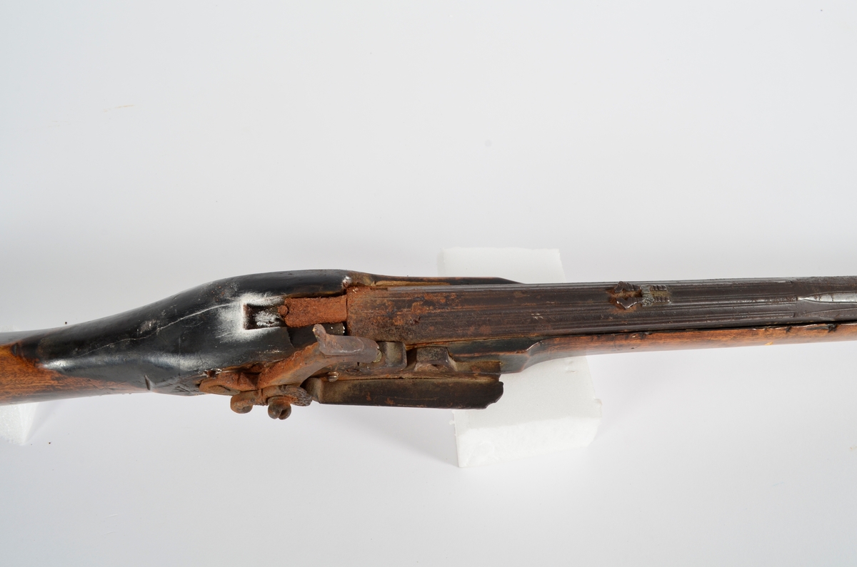Flintlåsgevær  med kolbe av bjørk. Avtrekkerbøylen har dekorterte beslag.