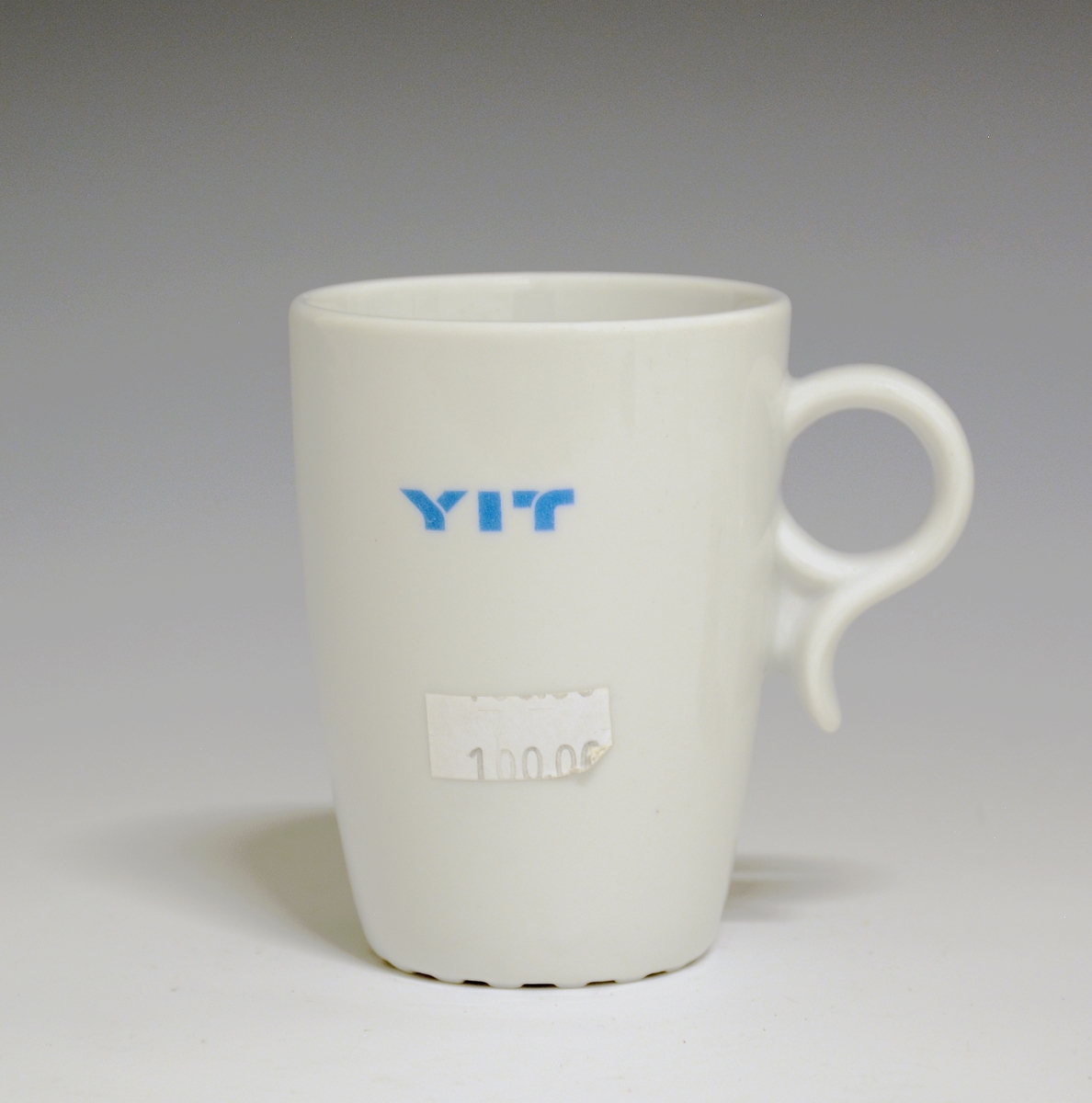 Krus av porselen med  hvit glasur. Trykkdekor med påskriften: "YIT".
Modell: 2731, Victor.
