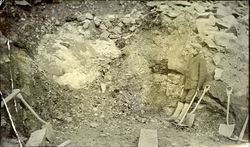 En mann med pipe i munnen foran en mulig gruveinngang på Sva