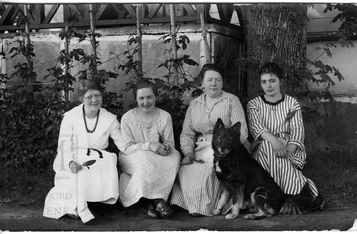 Fire kvinner samlet ute i en hage. Elever og lærer på husmorskole.