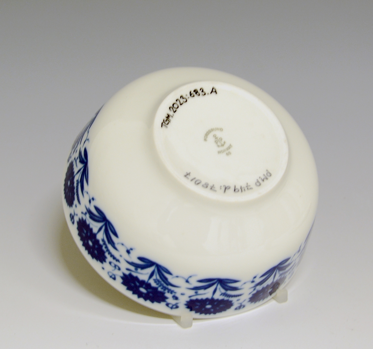 Sausebolle med fat, av porselen. Dekorert med blomsterdekor i blå iglasur trykkdekor.
Modell: Meny, 2310 av Tias Eckhoff, i produksjon fra 1955.
Dekor: Nellik av Anne-Marie Ødegaard fra 1957.