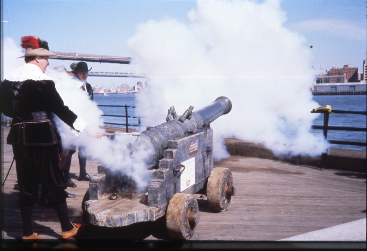 En kanon avfyras i New Yorks hamn i samband med 350-årsjubileet av kolonin Nya Sverige 1988. Två män i 1600-talsdräkter.