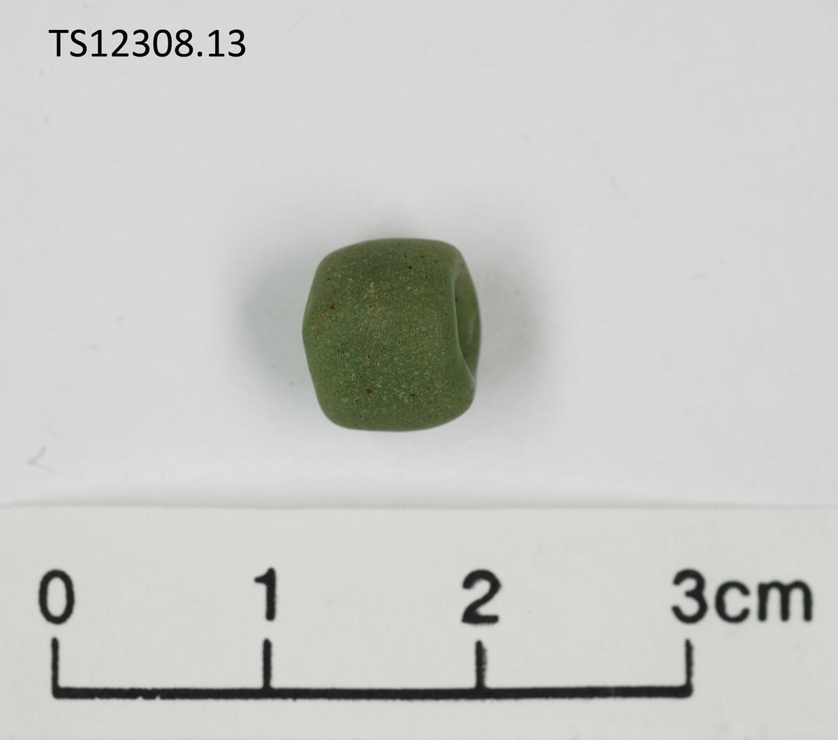 1 stk perle av glass. Grønn. 0,9 cm i diameter, 0,7 cm tykk.