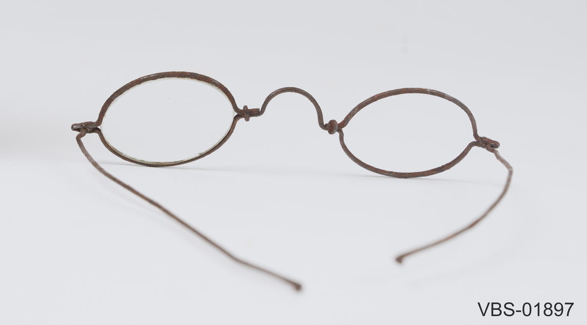Leddet innfatning med to stenger som kan brettes sammen/ strekkes ut. 
Tilnærmet smal, oval utformet front med tilpasset brilleglass.
