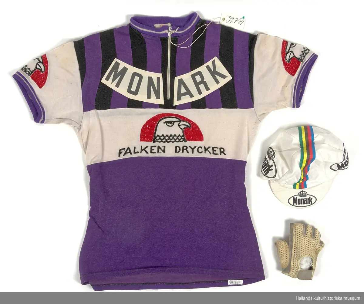 Cykeltröja i vit och lila syntet märkt: "MONARK". Tre fickor på ryggen, märkt: "MONARK" och "FALKEN DRYCKER" på både fram- och baksida. Även "Falkens" logotype på ärmarna.
Med tillhörande monarkkeps och en handske i bakfickor på tröjan.