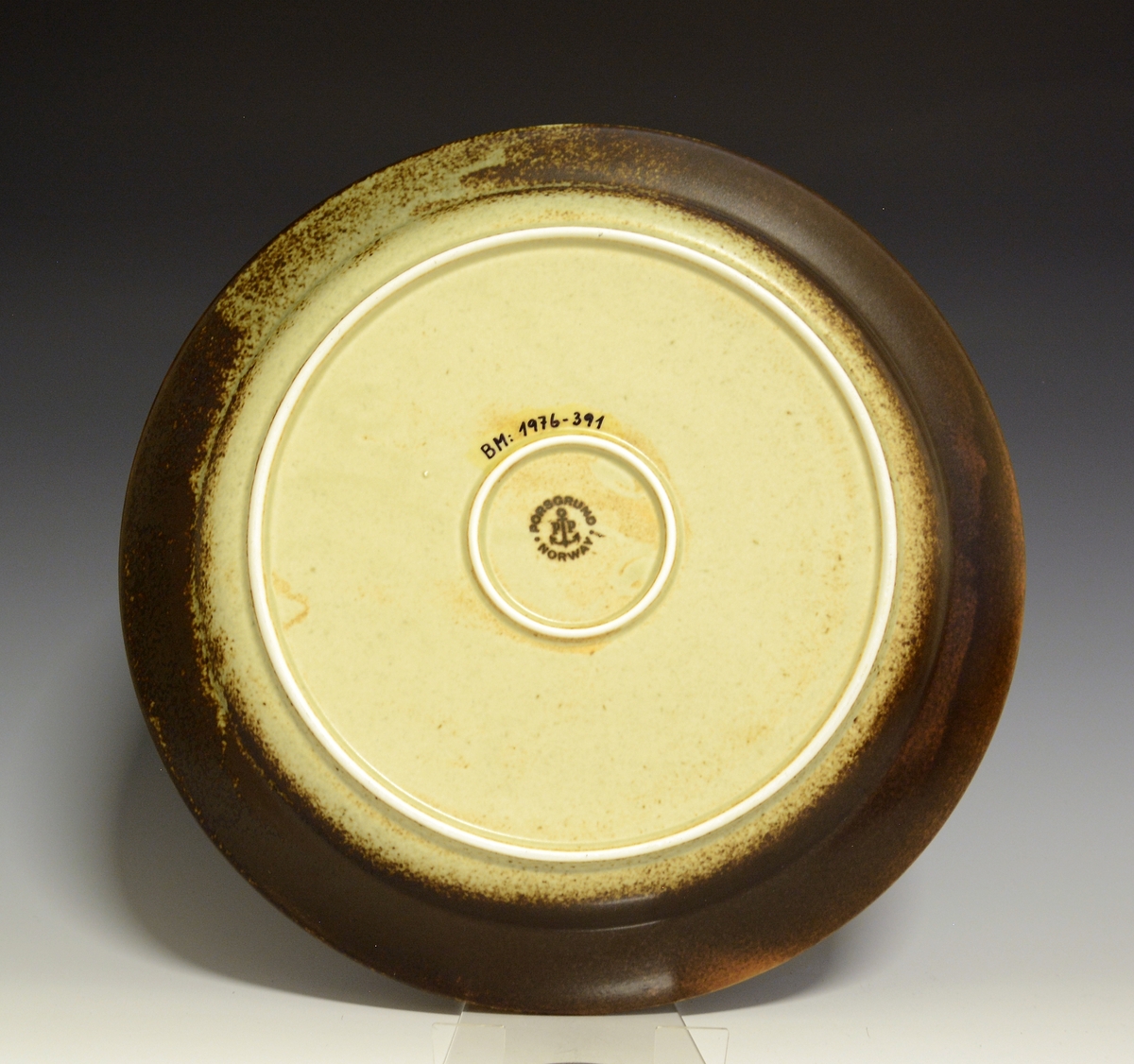 Prot: Fat av porselen, rundt. "Lava" lansert i 1972 av Porsgrunds Porselænsfabrik. Farver: Fra mørk brunt-lysebrunt-grønnaktig-en slags beige.
Modell: 2440/1, Eystein.
Dekor: 885258, Lava
