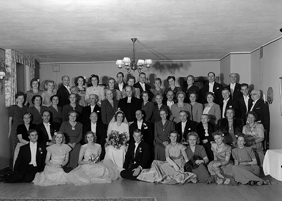 Brudpar omgivet av bröllopsgäster.
Fotografens ant: Henry Svensson.