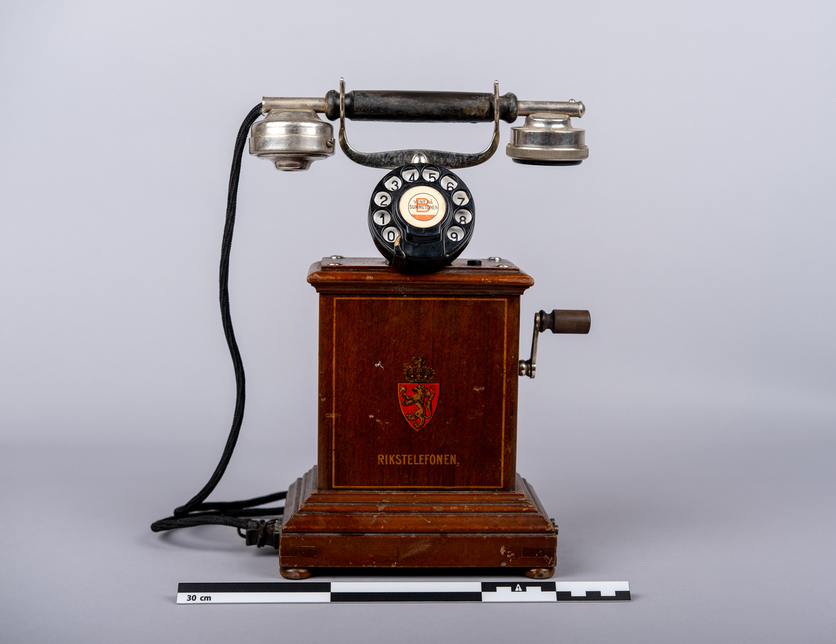 Rikstelefonenns bordtelefon fra 1918.
Telefonen består av telefonrør, telefon med tallskive, kabel og ledning. 
Tallskivet har tall 0-9.
Sveiv på høyre siden.  
På front siden riksvåpen med løven og kkronen, under det "RIKSTELEFON"-