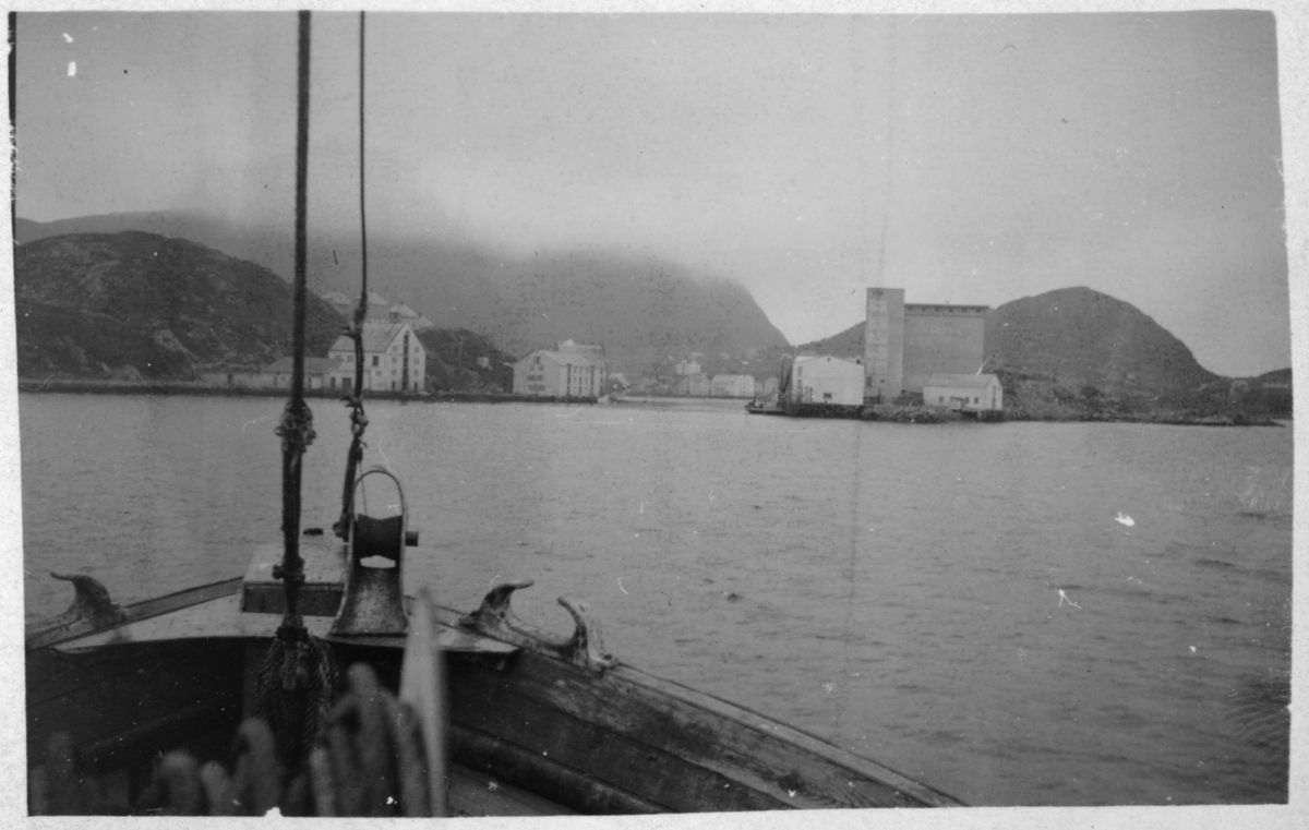 Bebyggelse og fjell, fotografert fra sjøsiden. Baugen på "Myregga" i forgrunnen.