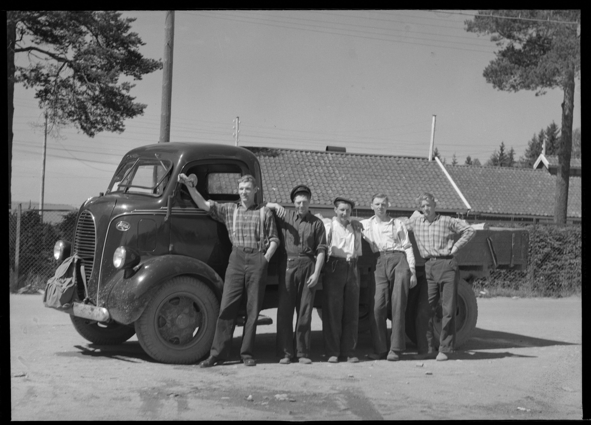 Fem menn oppstilt fremfor en varebil