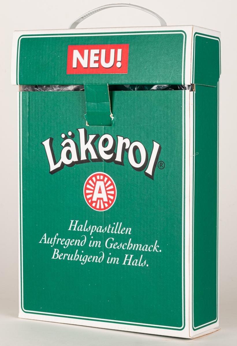 Reklamförpackning i papp, för tysk marknad. Grön med öppning upptill och vitt plasthandtag. Innehåller em t-shirt.