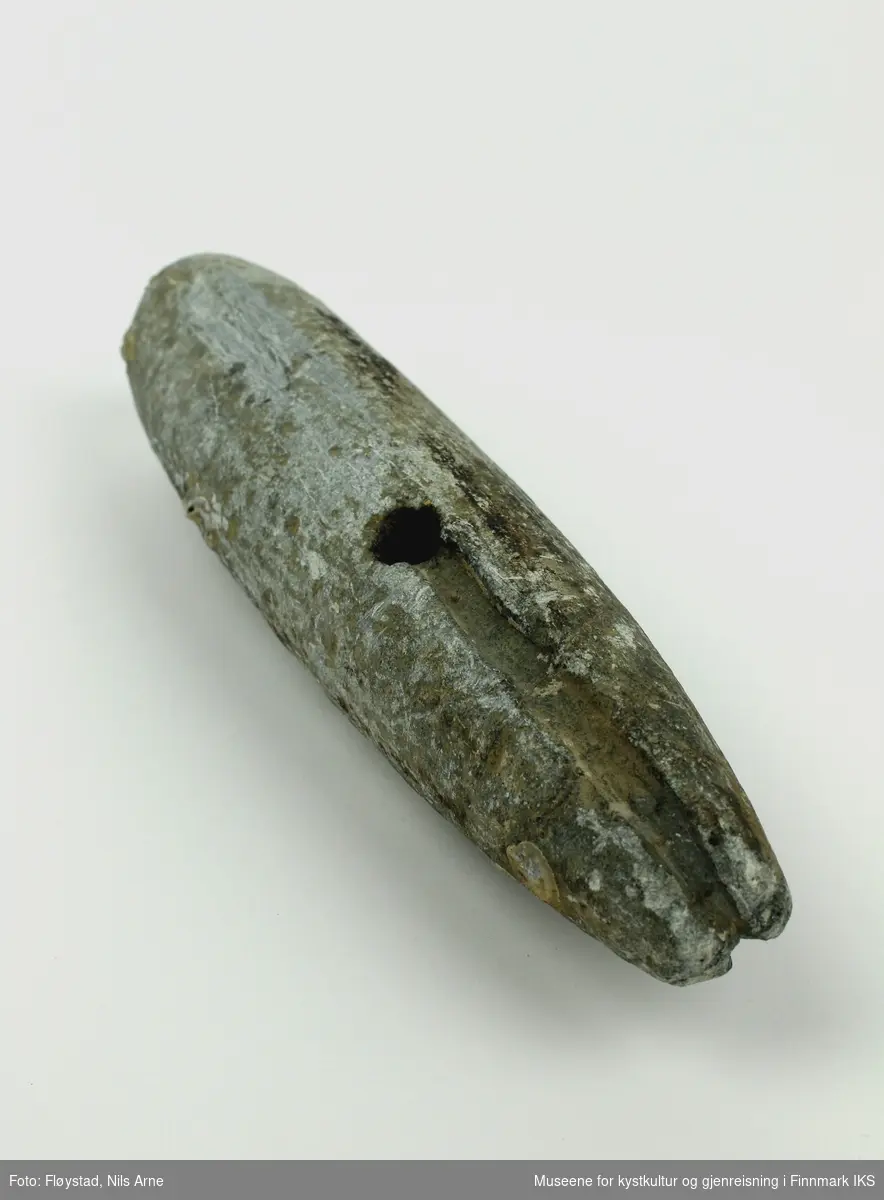 En avlang søkke, eller jarstein laget av stein med et gjennomgående hull og spor til snøre i den smale enden av steinen. Jarsteinen har en glatt overflate.