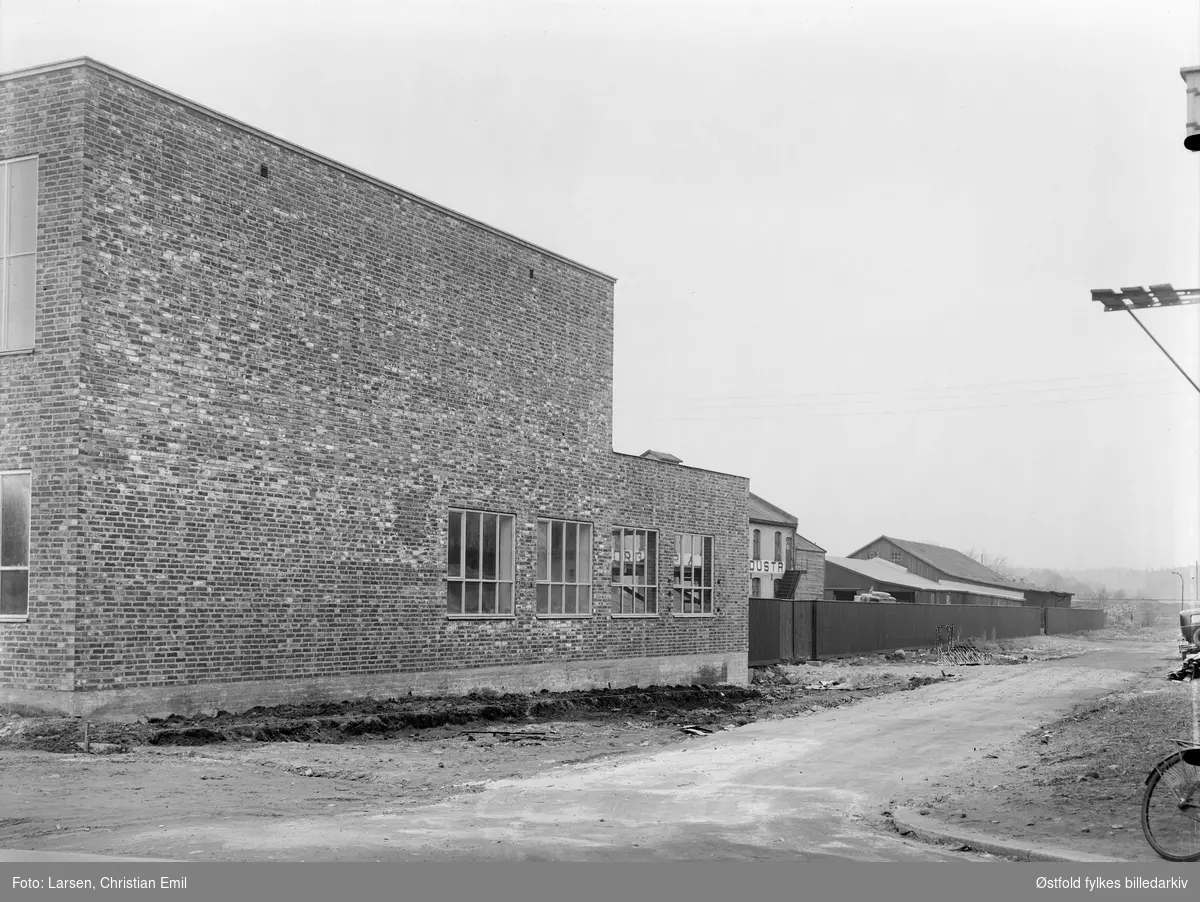 Sarpsborg Pap og Papirindustri AS, industribygning i 2. etasjer med bil foran. Ny og gammel fabrikkbygning.