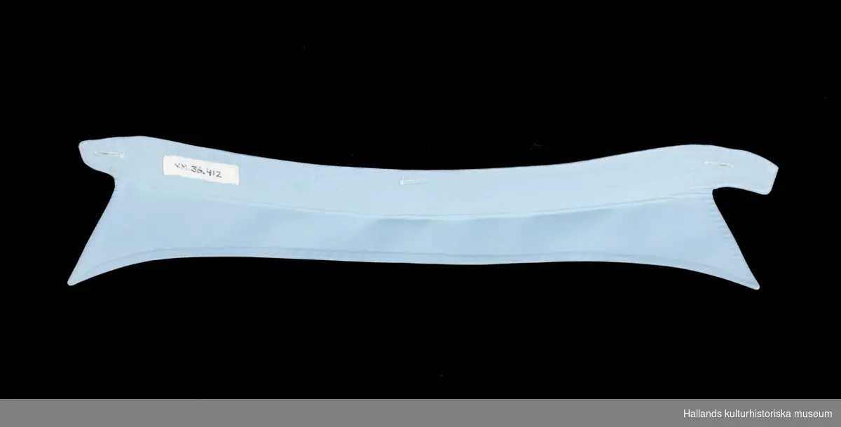 Skjortkrage i ljusblå bomullslärft. Rektangulär med nervikta snibbar. Märkt: "Monitor John Erikssons 330 62 storlek 39."